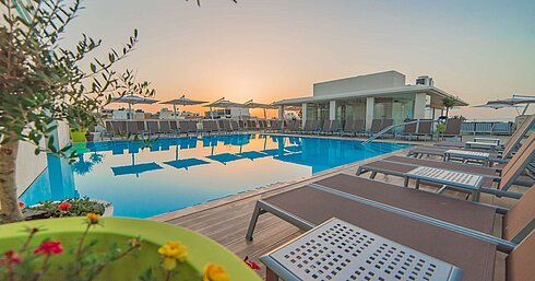 Pool Außenpool mit Sonnenliegen und Sonnenschirmen bei stimmungsvoller Abenddämmerung